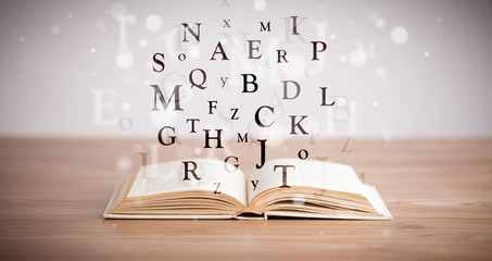 Opened book with flying letters