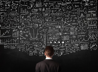 Businessman standing in front of drawn charts on a blackboard