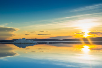 Plakaty  Topniejąca góra lodowa na wiosennym górskim jeziorze w zachodzącym słońcu.