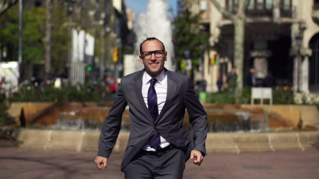 happy businessman running towards the camera and jumping up with