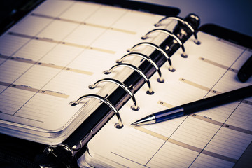 Personal organizer or planner with pen on white background