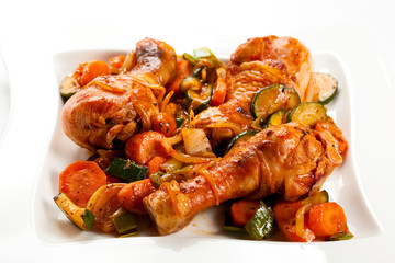 Grilled chicken legs and vegetables on white background