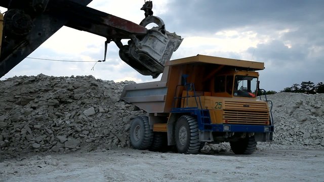Heavy mining dump truck being loaded with iron ore