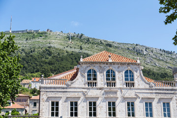Old Stone Building with Red Tile Roof Under Green Dubrovnik Hill