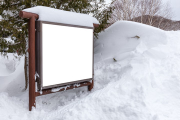 Billboard covered with snow on the background of the park