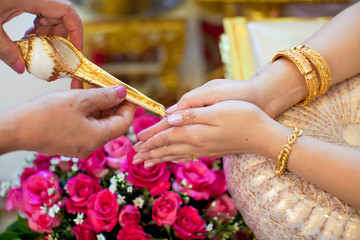 hand of a bride receiving holy water from elders
