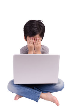 Little boy in front of laptop hiding his face