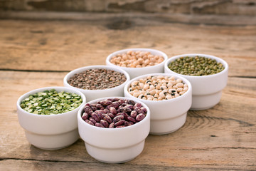 Six bowls with cereals on wooden desk.