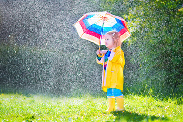 Funny toddler with umbrella playing in the rain
