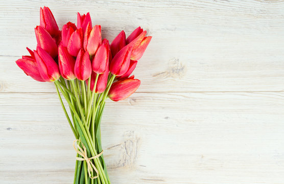 bunch of red tulips on wooden surface