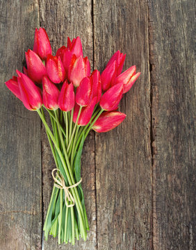 bunch of red tulips on wooden surface