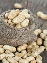 peanuts in a miniature burlap bag on wooden surface