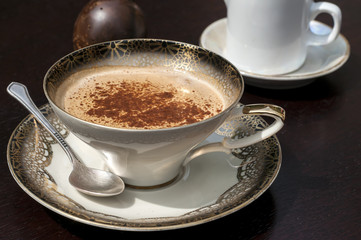 Fine porcelain cup with coffee, milk and sprinkled cinnamon