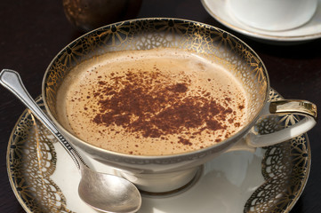 Fine porcelain cup with coffee, milk and sprinkled cinnamon