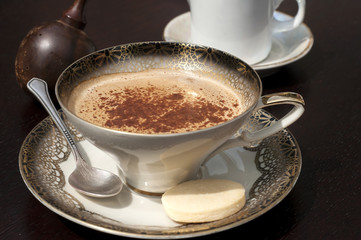 Fine porcelain cup with coffee, milk and sprinkled cinnamon