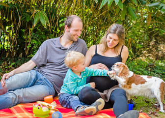 Happy family with their pregnant mother having picnic in park