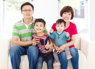 happy asian  family sitting on a white leather sofa