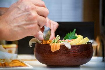 Hands of a Japanese Chef make a bowl of Sushi
