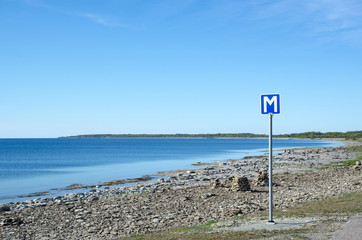 Scandinavian passing place road sign by a road along a flat rock
