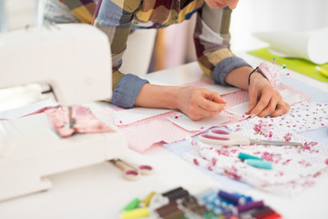 Closeup on seamstress working in studio - obrazy, fototapety, plakaty