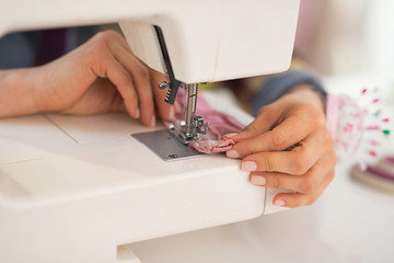 Closeup on seamstress sewing in studio - obrazy, fototapety, plakaty