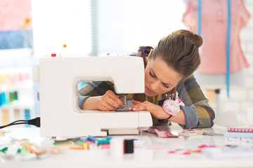 Seamstress working with sewing machine - obrazy, fototapety, plakaty