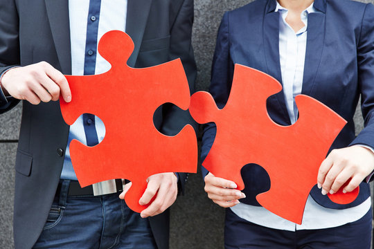 Gesch&auml;ftsleute halten zwei gro&szlig;e Puzzleteile