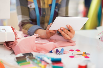 Closeup on seamstress using tablet pc at work