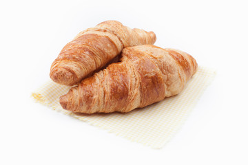 Fresh and tasty croissant on yellow checkered napkin over white