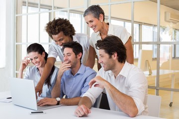 Business people laugh while looking at laptop