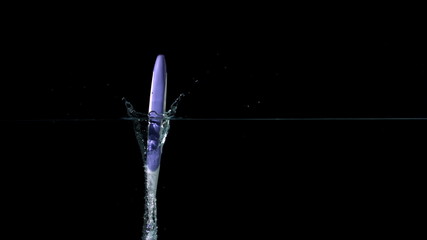 Purple toothbrush falling in water on black background - Powered by Adobe