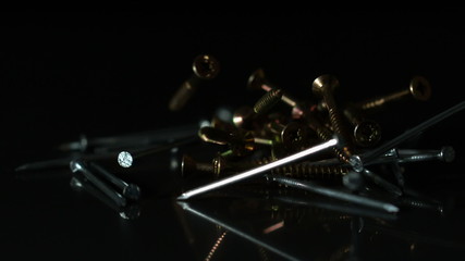 Nails and screws falling on black surface - Powered by Adobe