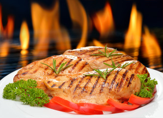 Grilled chicken breast with vegetables on white plate.