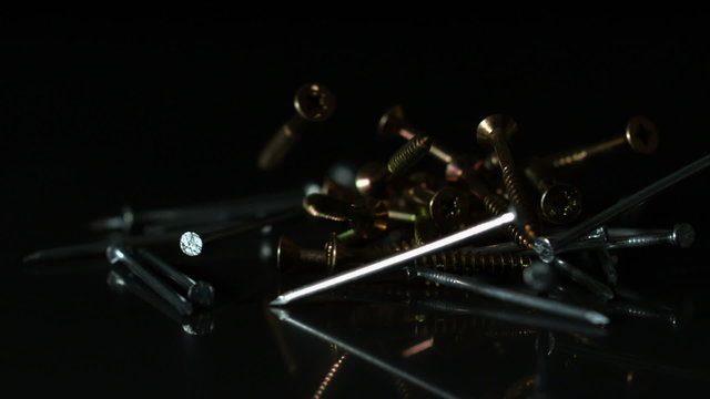 Nails and screws falling on black surface - Powered by Adobe