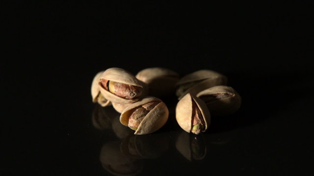 Pistachio nuts falling on black surface
