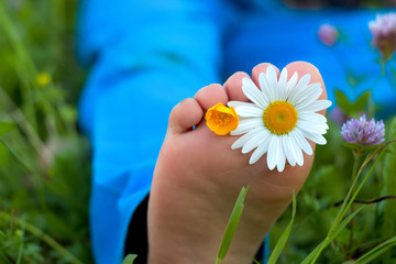 Kinderfuss mit zwei Blumen zwischen den Zehen