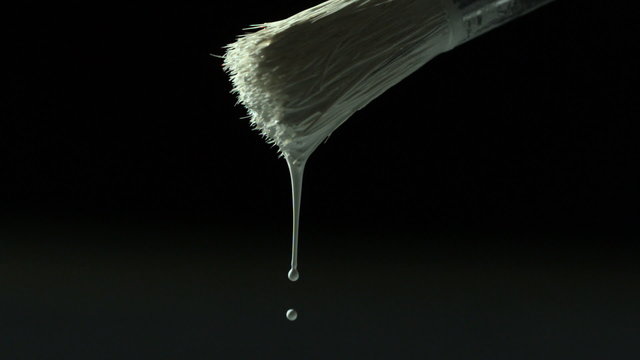 White paint dripping from paintbrush