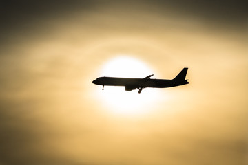 Fototapeta na wymiar Samolot pasażerski lecący przed zachodem słońca