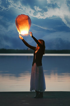 Chinese sky lantern and young woman at dusk