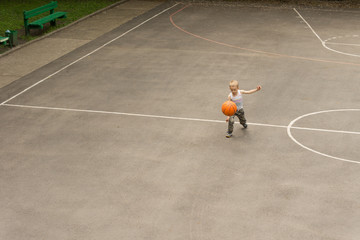 Small boy playing basketball bouncing the ball