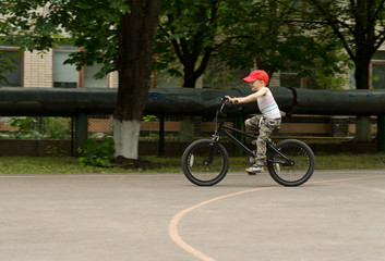 Young boy riding his bike on a basketball court