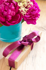 Flowers and present box with ribbon on table.Birthday gift..