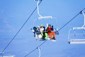 Fototapeta na wymiar Three young people with snowboarders on ropeway