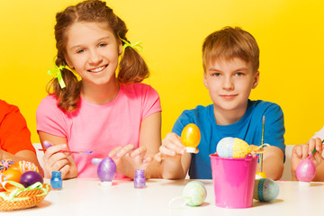 Obraz na płótnie Canvas Boy and girl painting Easter eggs at the table