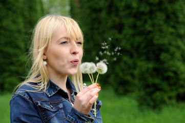 Beautiful young woman blowing a dandelion