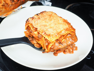 Lasagna being served onto grey plate