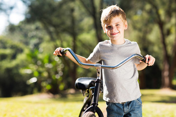 little boy walking with a bike