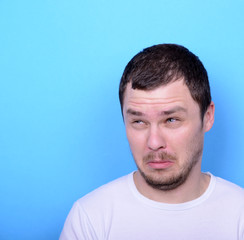 Fototapeta premium Portrait of man with dusgusted gesture against blue background