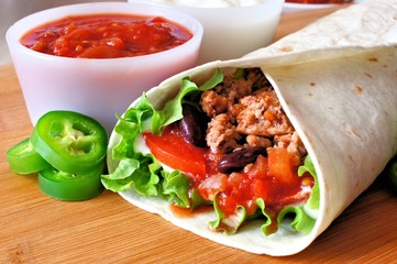 Close up of a burrito filled with meat and vegetables - obrazy, fototapety, plakaty