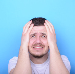 Portrait of sad man looking up against blue background